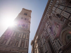 Giotto's Campanile in Florence with a sunburst and portion of the southern facade of Santa Maria del Fiore.