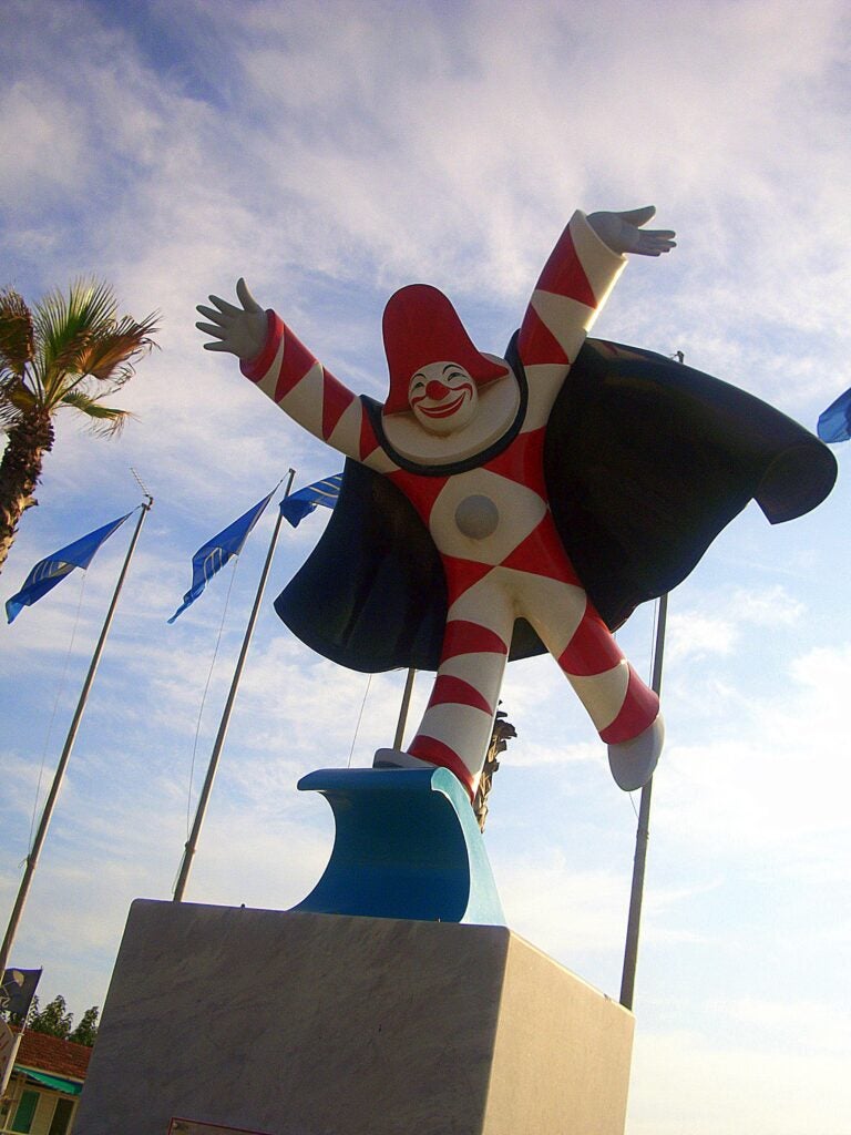 A statue of the Carnevale's mascot, Burlamacco, dressed in red and white alternating colors and a black cape.