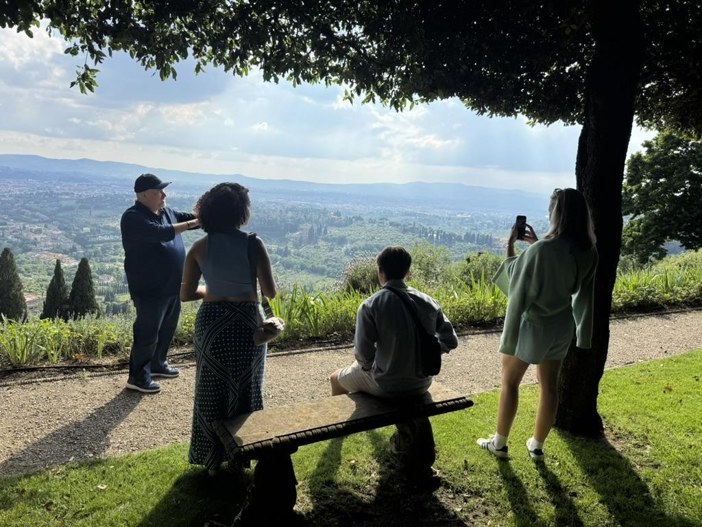 Three students sit and stand in the Ilex grove as Fulvio Orsitto explains the grounds.